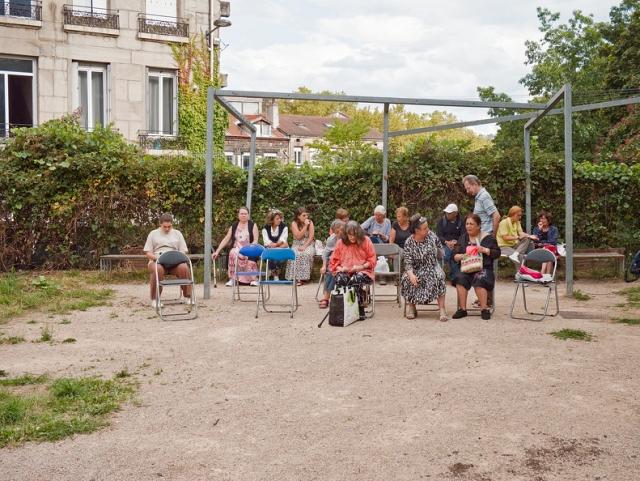 Un petit public attend un spectacle dans un square en ville