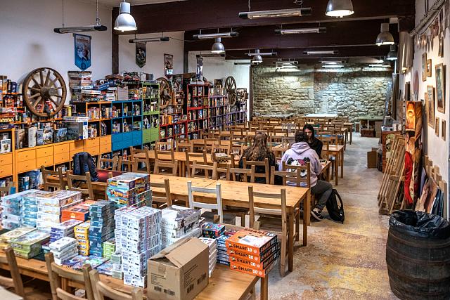 Une salle assez grande avec de longues tables et une ludothèque sur le coté.