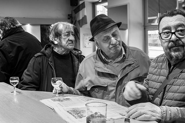 Homme accoudés au bar autour d'un journal et de quelques verres.