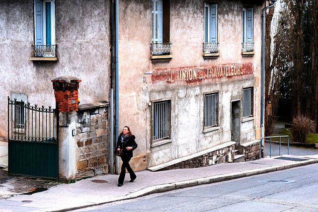 Le local en rez-de-chaussée de l'Union des travailleurs. Une femme passe sur le trottoir attenant.