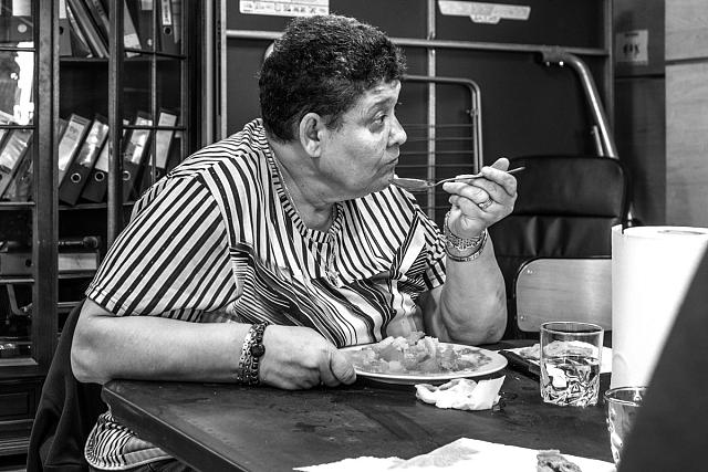 Une femme attentive assise à table tenant son assiette et prête à manger.