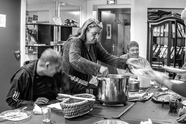 Une femme debout sert la nourriture sortie d'une grande casserolle.