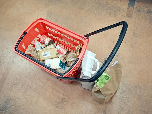 Divers fromages, conserves de tomates, farine dans un panier de supermarché.